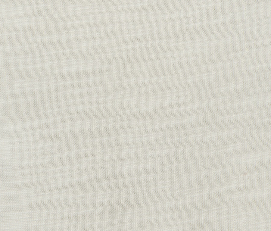 Detailansicht eines cremefarbenen Langarmshirts mit Rüschen.