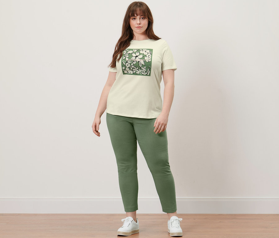 Frau steht in T-Shirt mit Print und Stretchhose.