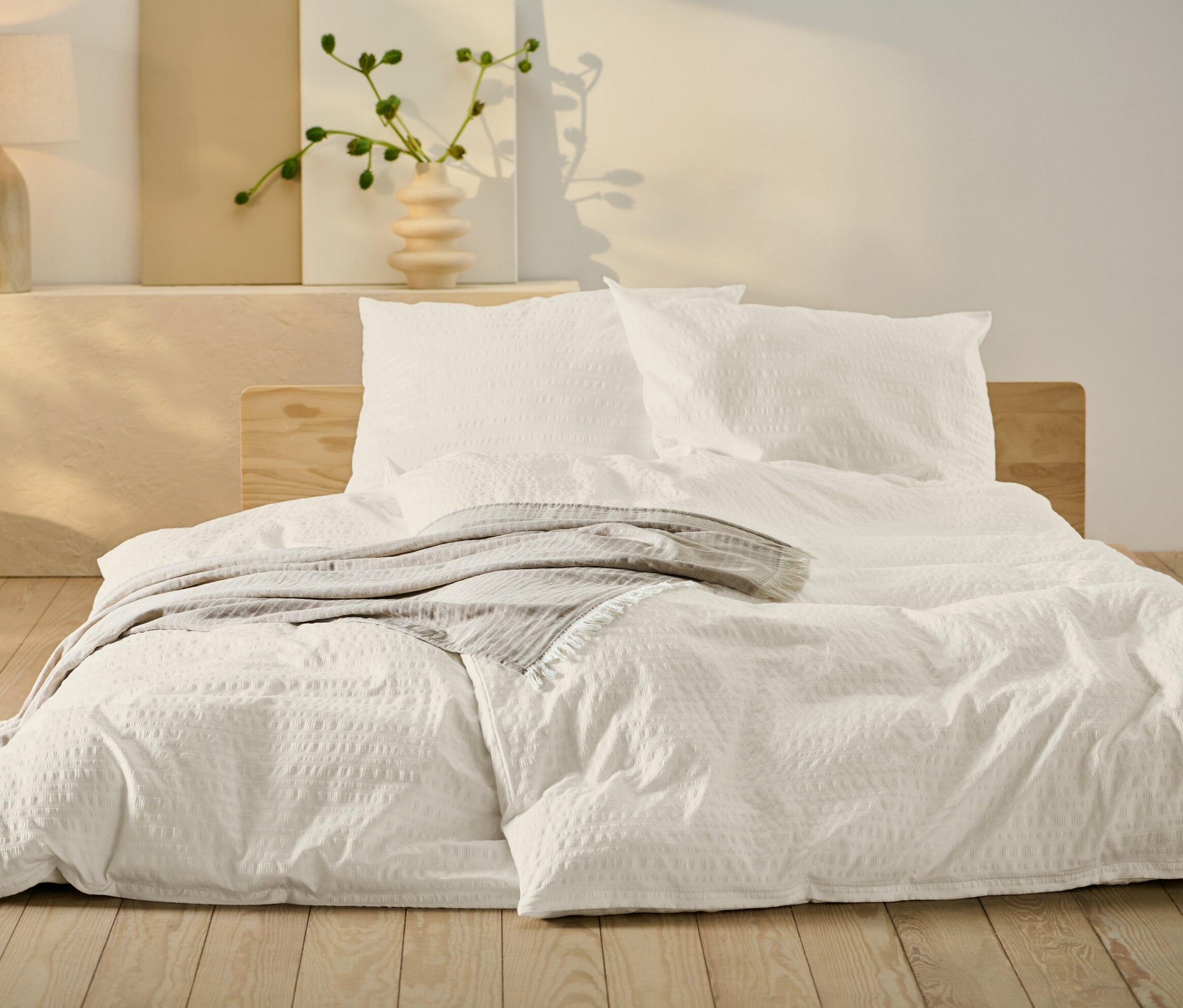 Schlafzimmer mit offweißer Seersucker-Bettwäsche in Normalgröße und Übergröße.