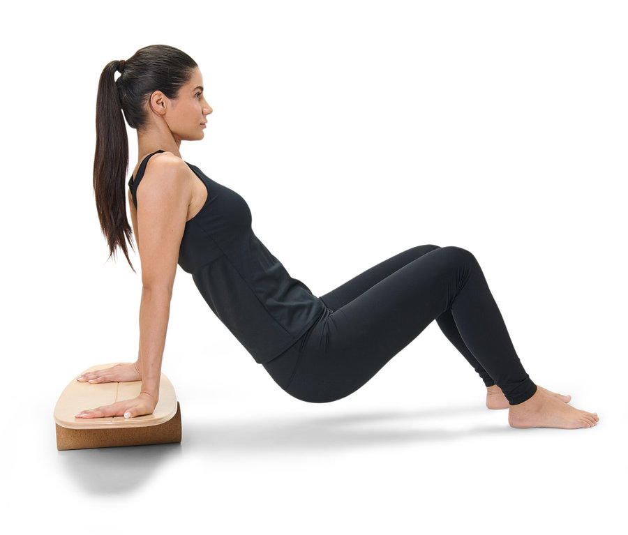 Frau in Sportkleidung macht Plank-Übung auf Balance-Board.