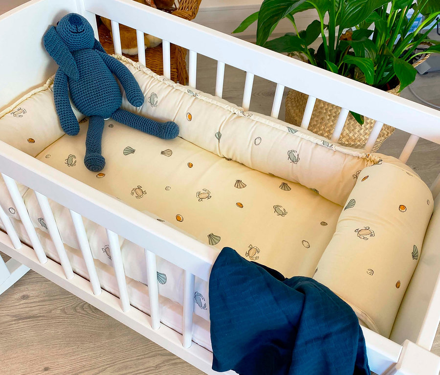Weiße Hoppekids Babywiege, ca. 40 x 80 cm, mit beigem Kissen und blauem Stoffhasen.