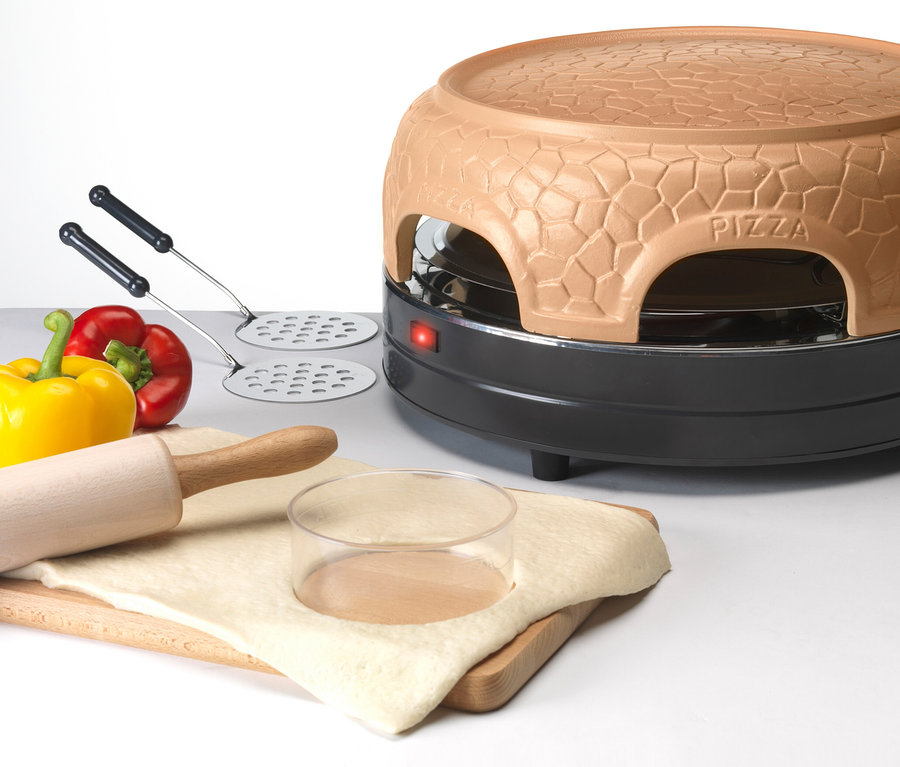 Ein Pizzaofen steht neben einer gelben und roten Paprika, einem Nudelholz und aufgegangenem Teig.