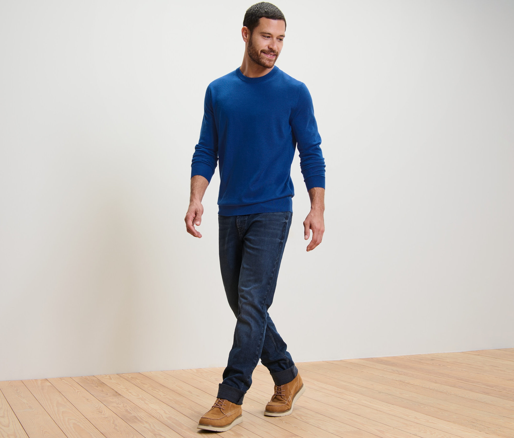 Mann geht und trägt einen blauen Merino-Pullover.