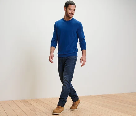 Mann geht und trägt einen blauen Merino-Pullover.