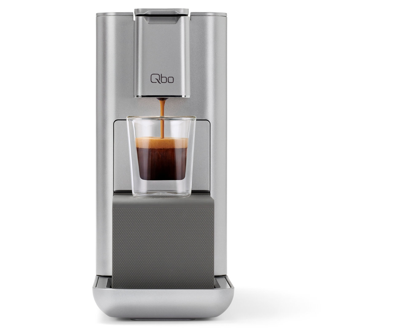 Kaffee fließt aus einer silbernen Qbo Kaffeemaschine in ein Glas.