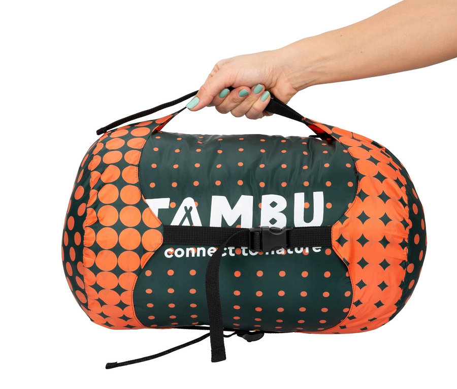 Eine Hand hält einen zusammengerollten Tambu Mumienschlafsack »KARA 1600«.