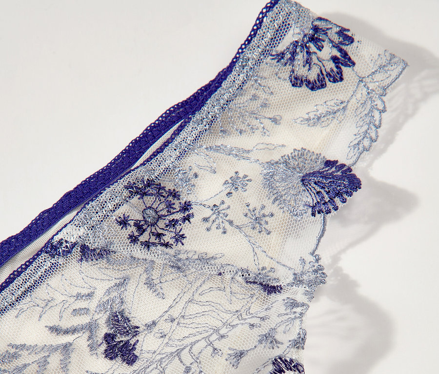 Detailansicht der weißen Passionata Tanga »Chloe« mit blauer Blumenstickerei.