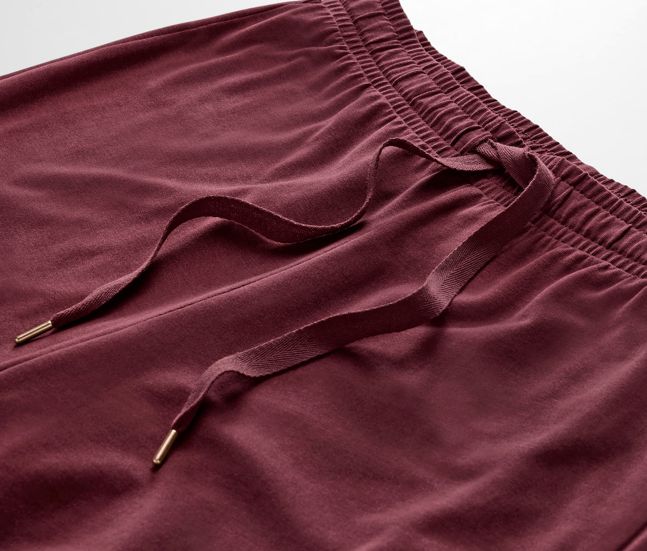 Detailaufnahme einer bordeauxroten Trainingshose mit Kordelzug.
