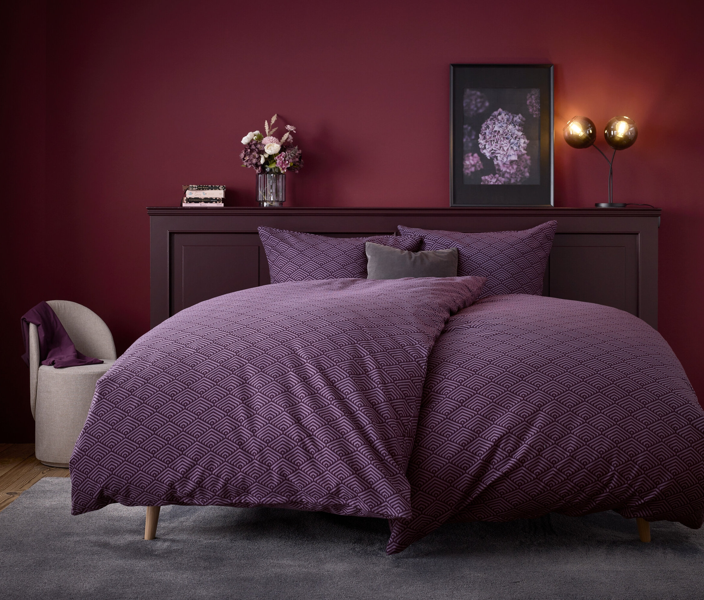 Lila geometrische Bettwäsche auf einem Bett mit einem Kopfteil aus dunklem Holz.
