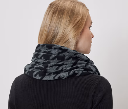 Frau trägt einen grau-schwarzen Hahnentritt-Schal und einen schwarzen Pullover.