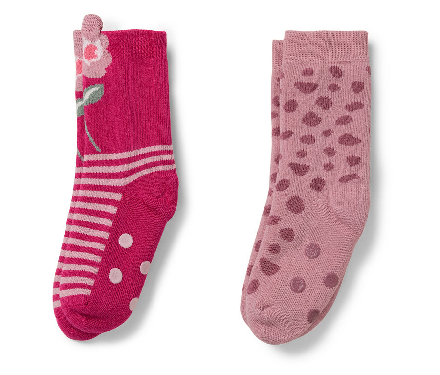 Zwei Paar Socken. Ein Paar rosa mit Blumenmuster, das andere hellrosa mit Punkten.