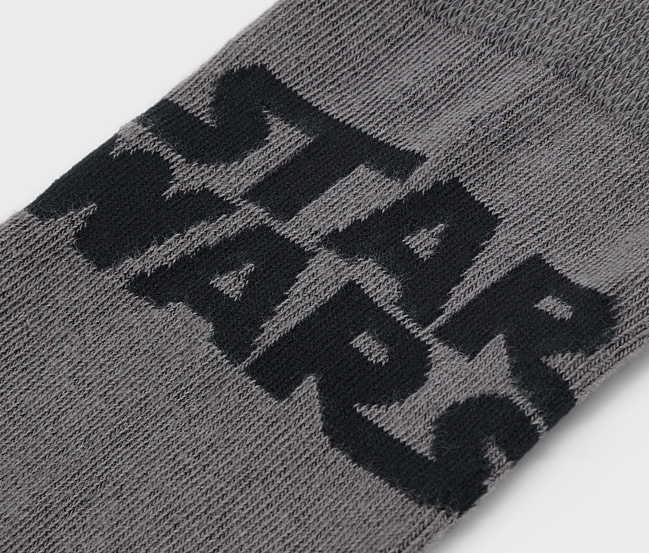 Detailaufnahme einer grauen Socke mit schwarzem STAR WARS Schriftzug.