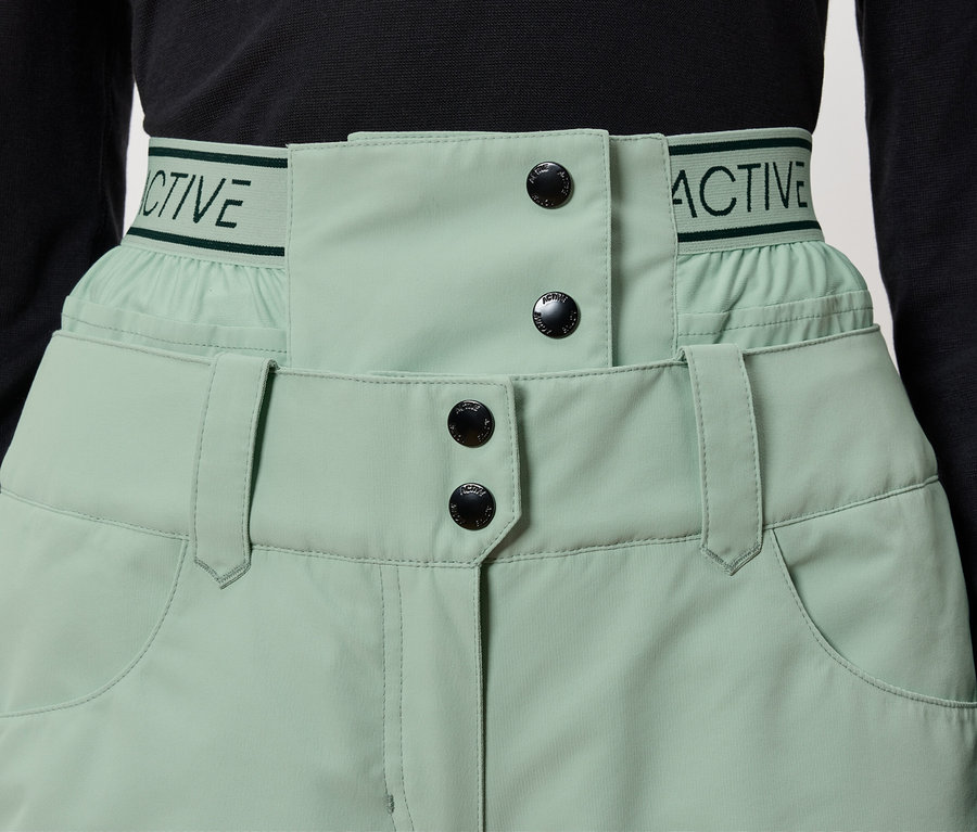 Detail einer hellgrünen Hose mit schwarzen Knöpfen und dem Schriftzug "ACTIVE" am Bund.