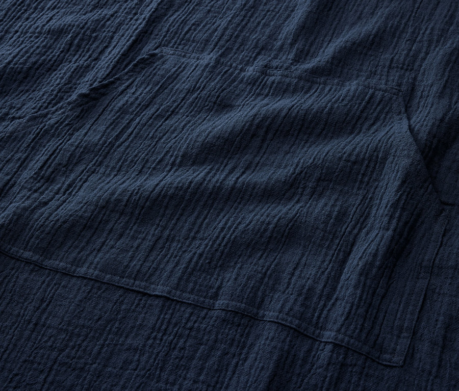 Detailansicht eines marineblauen Musselin-Umzieh-Ponchos mit Tasche.