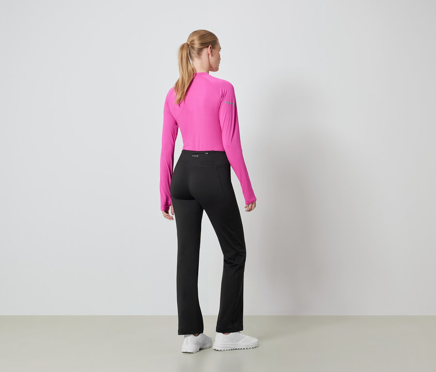 Frau mit dem Rücken zur Kamera trägt ein pinkes Langarmshirt und eine schwarze Hose.
