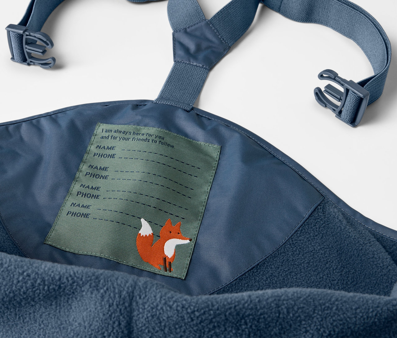 Detailaufnahme einer blauen Kinder-Thermo-Regenhose mit Latz und Etikett mit Fuchs.