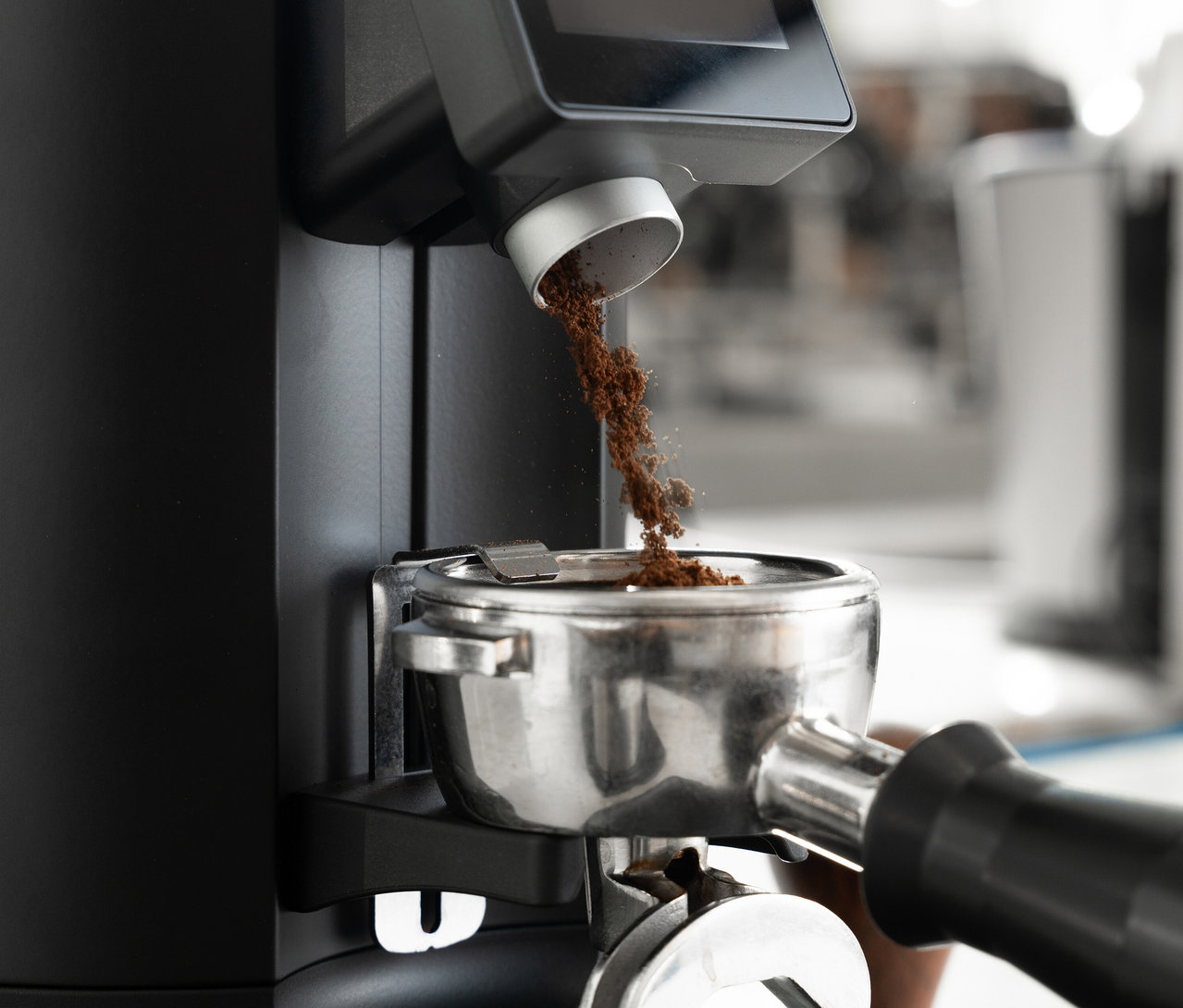 Kaffeepulver fällt aus einer Kaffeemühle in einen Siebträger.