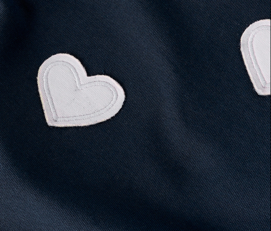 Nahaufnahme eines dunkelblauen Stoffes mit weißen Herzapplikationen.