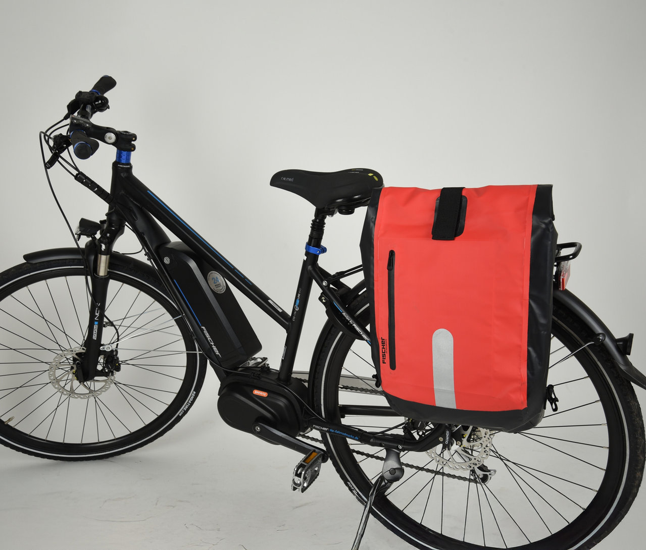Schwarzes Fahrrad mit FISCHER wasserdichter Gepäckträgertasche in Rot und Schwarz am Gepäckträger.