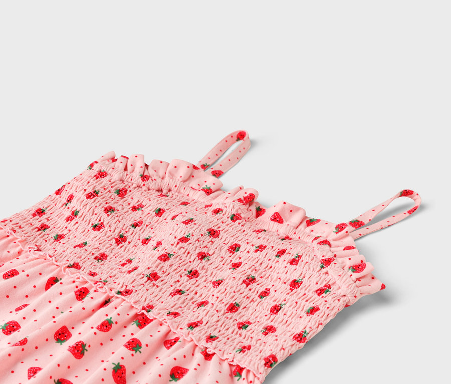 Nahaufnahme eines rosa Kleides mit Erdbeermuster, geraffter Brustbereich und Rüschen.
