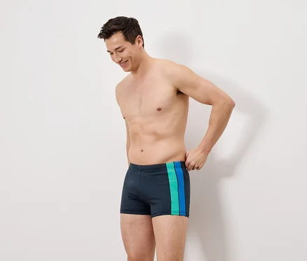 Mann trägt dunkelblaue Badehose mit grünen und blauen Streifen.