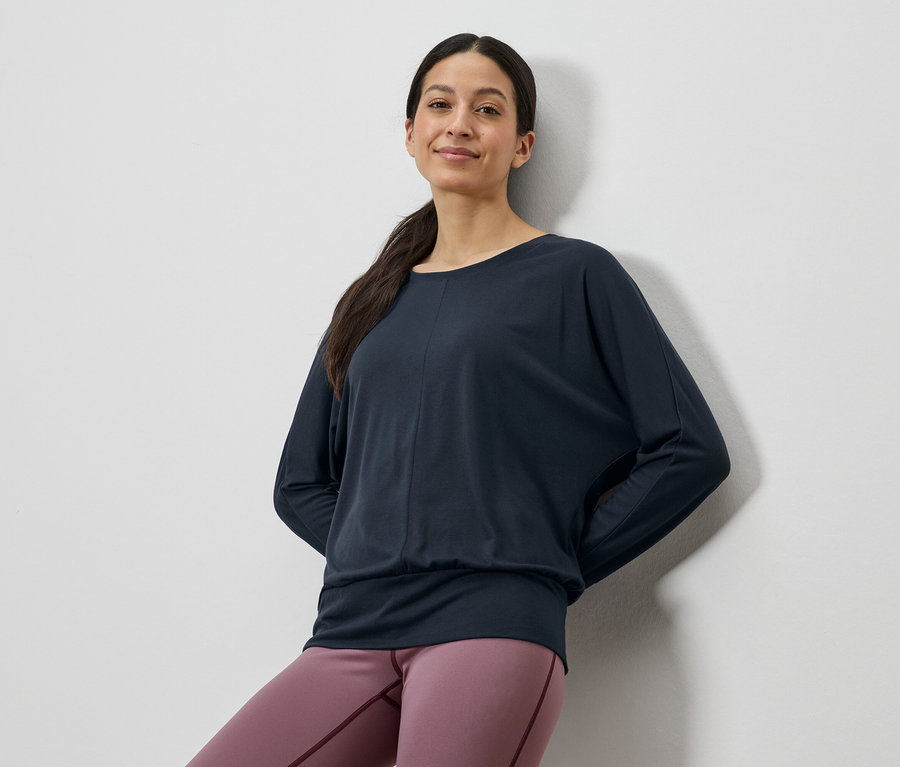 Frau trägt ein dunkelblaues Langarmshirt und rosafarbene Leggings.