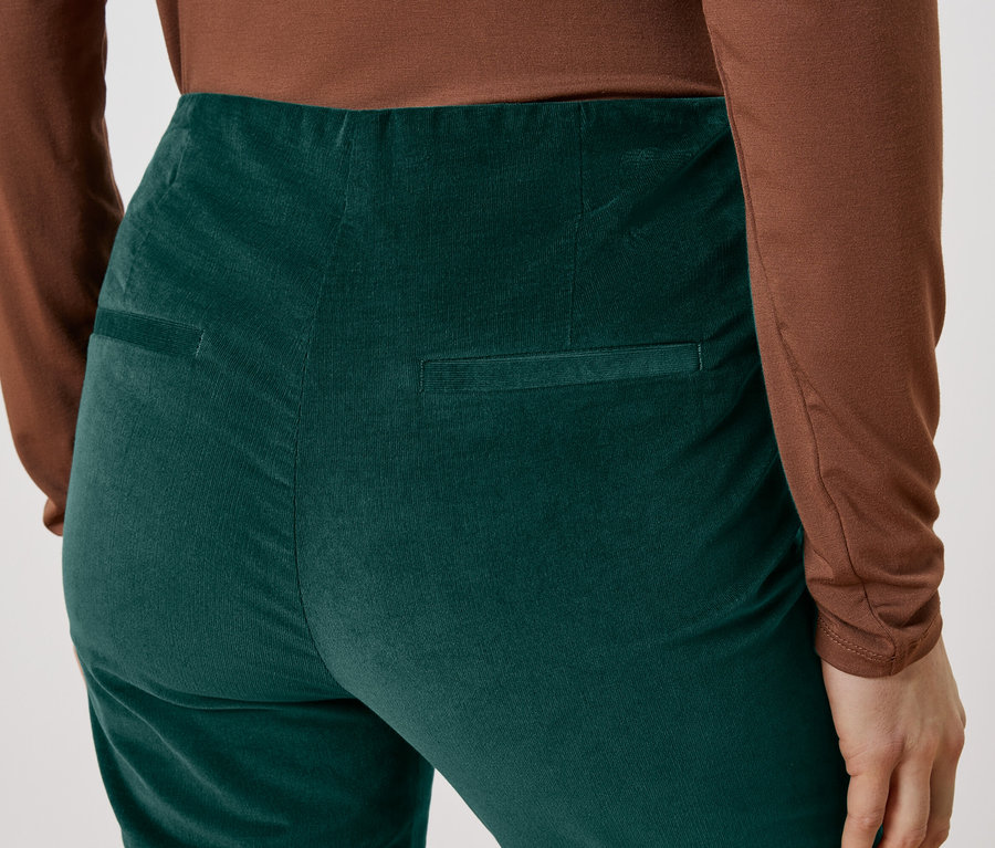 Nahaufnahme der Rückseite einer Person, die eine grüne Cordhose und ein braunes Oberteil trägt.