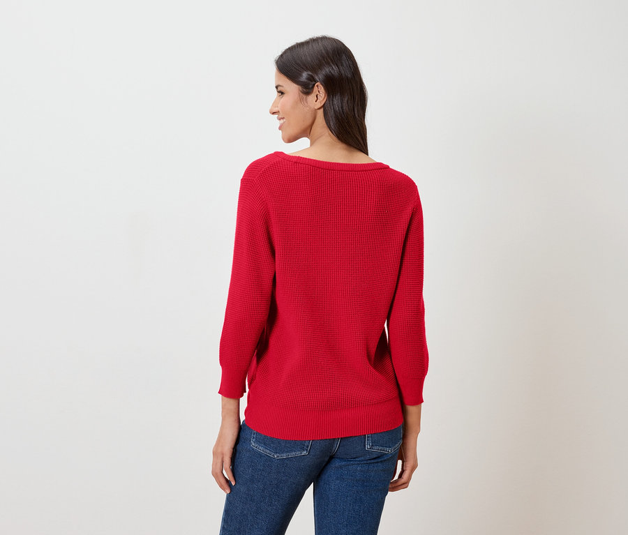 Frau von hinten, trägt einen roten Feinstrickpullover und Jeans.