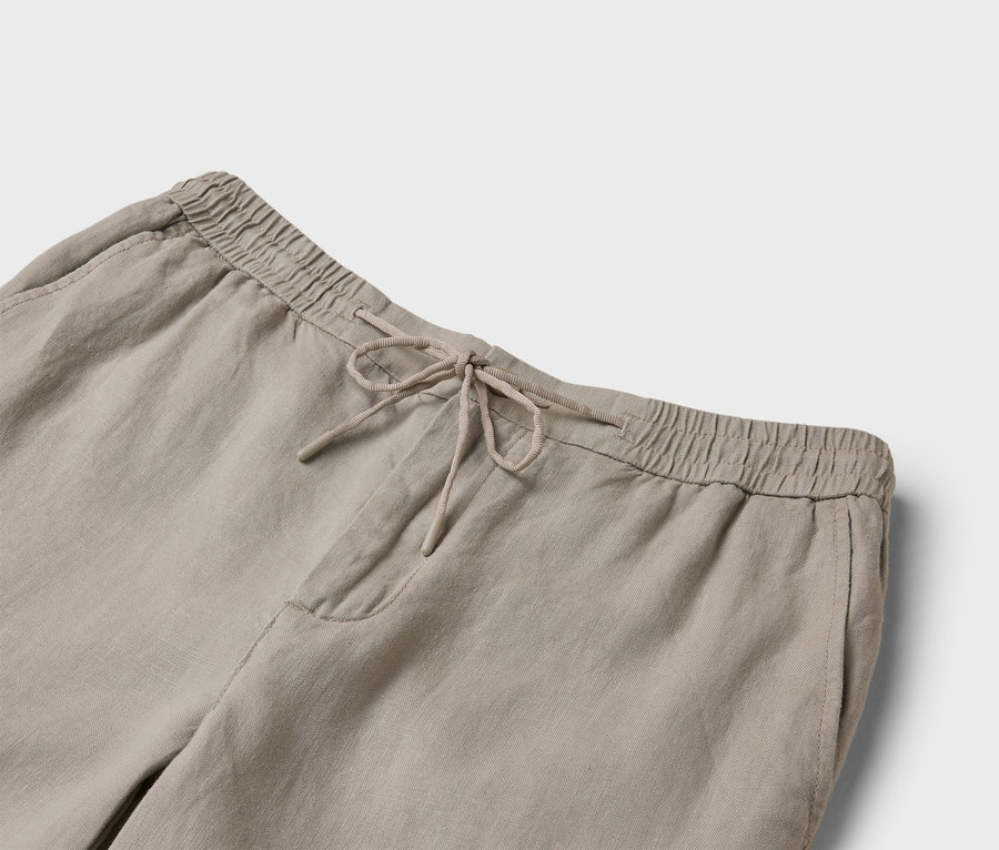 Nahaufnahme einer beigen Leinenhose mit Kordelzug und elastischem Bund.