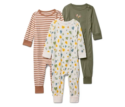 Drei Baby-Schlafanzüge liegen: gestreift in Braun und Weiß, mit Blättern bedruckt und einfarbig olivgrün mit Igel-Motiv.
