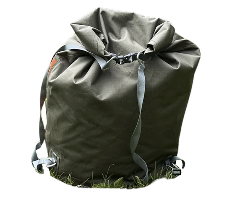 Der Tambu Wasserdichter Packsack »JOLA 80« in Olivgrün steht auf Gras. Er ist oben mit grauem Gurtband verschlossen.