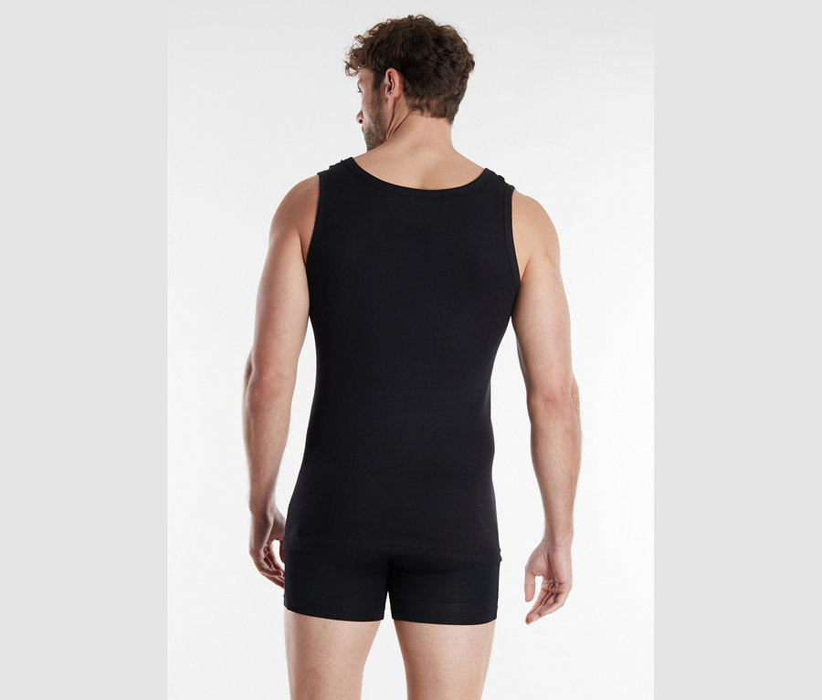 Mann von hinten in schwarzem Unterhemd und Shorts vor weißem Hintergrund.