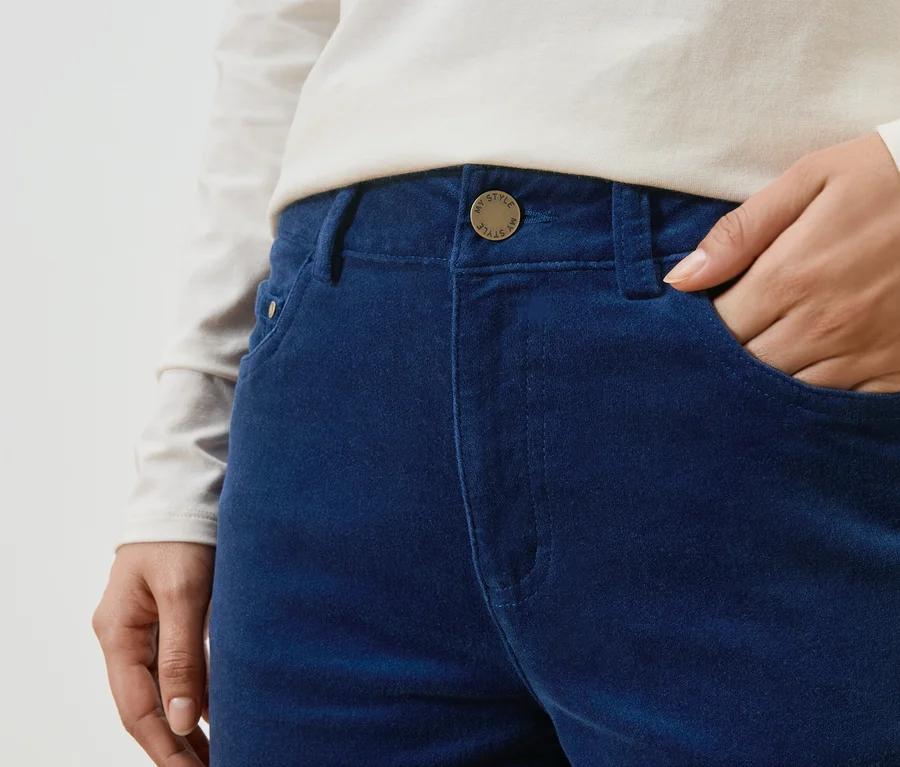 Eine Person mit einer Hand in der Hosentasche einer blauen Hose mit einem Knopf mit der Aufschrift "My Style".