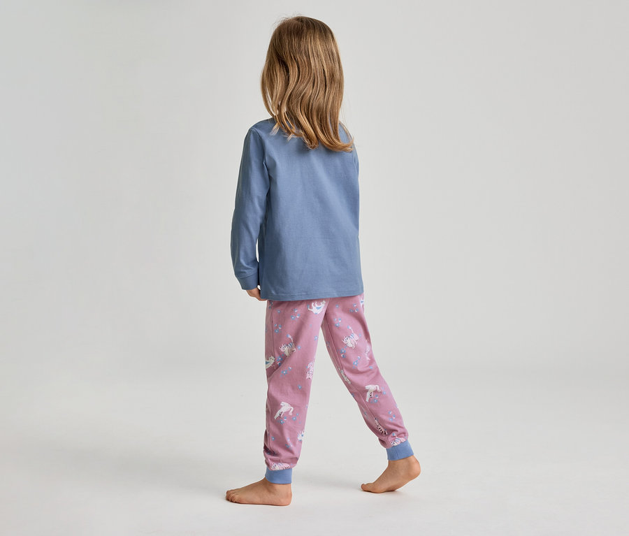 Ein Kind, von hinten gesehen, mit langen braunen Haaren, trägt ein blaues Langarmshirt und eine rosa Pyjamahose mit Einhorn- und Sternenmuster. Das Kind steht barfuß auf einem hellgrauen Boden.