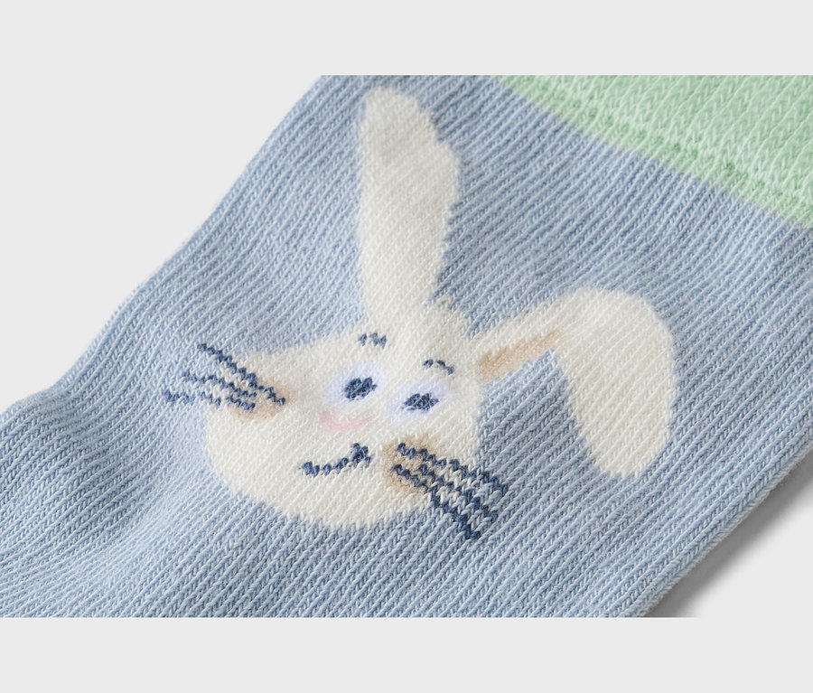 Nahaufnahme einer hellblauen Socke mit einem aufgestickten Hasenmuster.