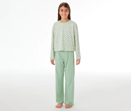 Lächelndes Mädchen in einem SCHIESSER Kinder-Interlock-Pyjama. Das Oberteil ist hellgrün-weiß kariert, die Hose hellgrün.