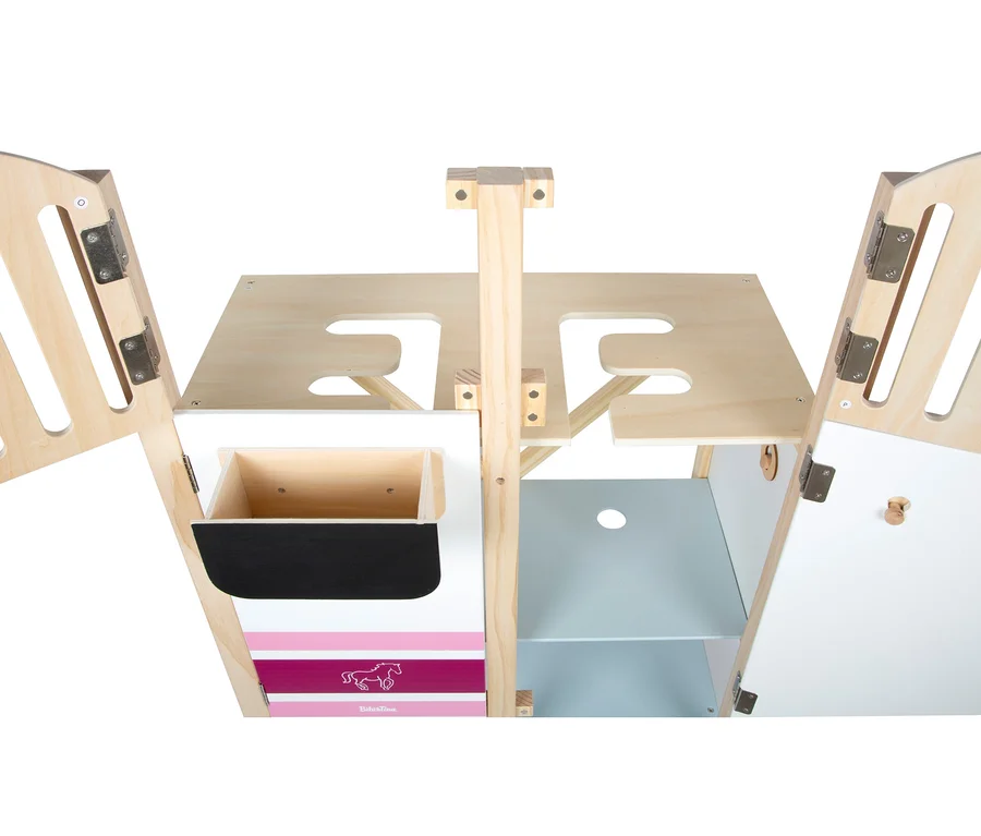 Ein teilweise geöffneter Holzspielzeugstall oder Spielhaus, das sein Inneres zeigt. Die Struktur hat Naturholz, weiße Paneele, rosa Streifen mit einer Pferdesilhouette und eine schwarze Kreidetafel. Im Inneren befinden sich Regale und Fächer, mit Aussparungen an den oberen Paneelen.