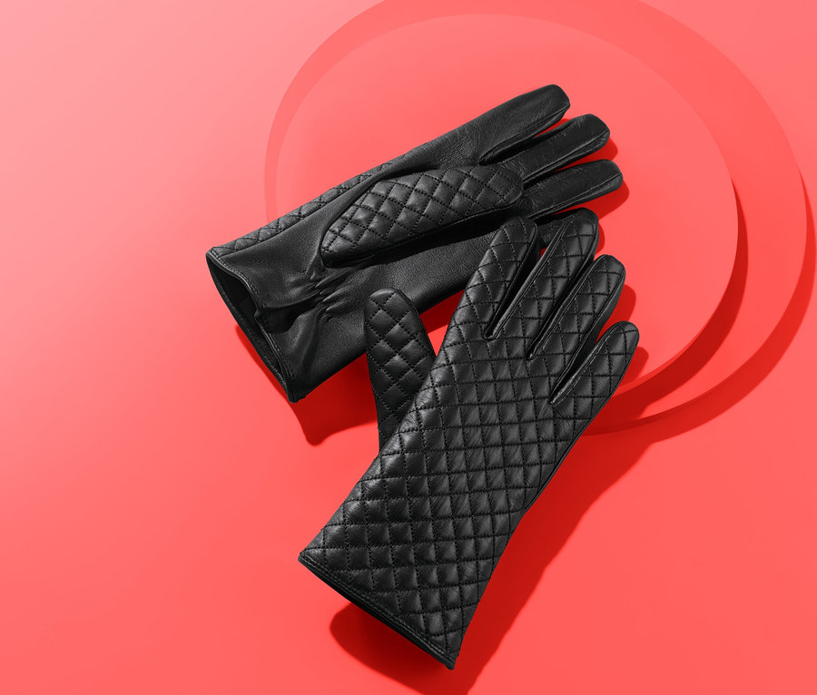 Zwei schwarze Lederhandschuhe auf rotem Grund.