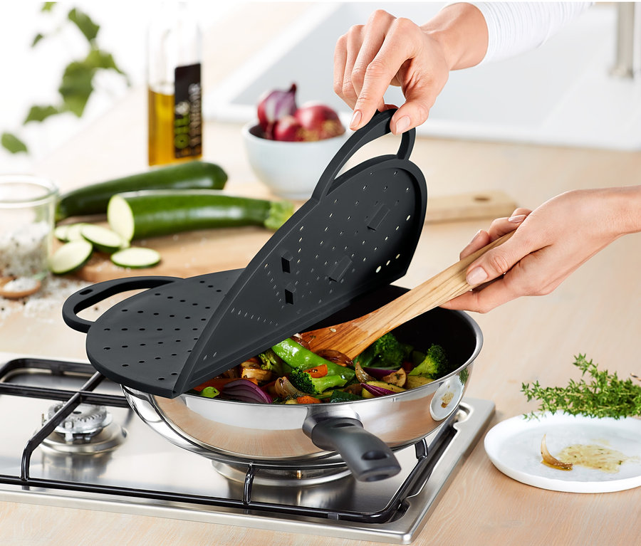 Person verwendet Küchen-Allrounder als Deckel für eine Pfanne mit Gemüse.