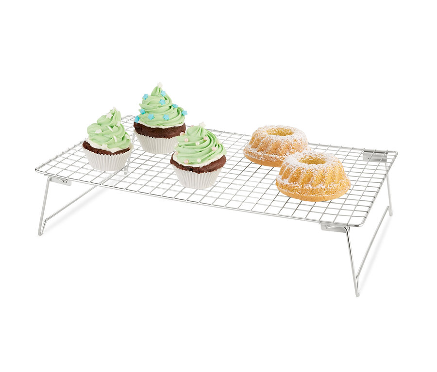 Drei Muffins mit grüner Dekoration und zwei Gugelhupfe mit Puderzucker auf einem 3-stöckigen Kühlgitter.