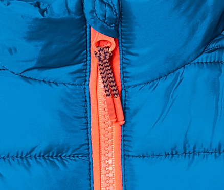 Detail einer blauen Steppjacke mit Farbverlauf und orangefarbenem Reißverschluss.