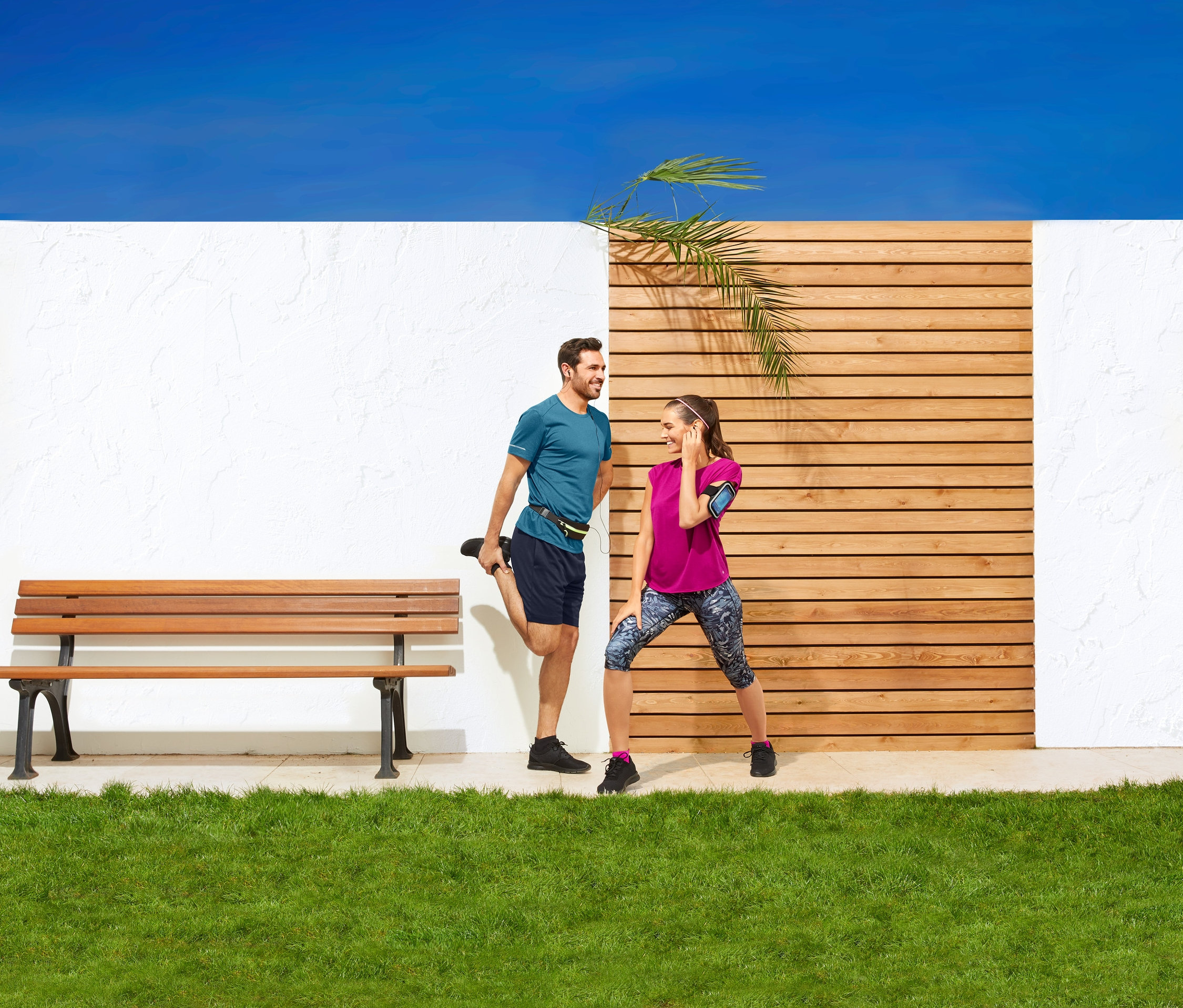 Mann dehnt Bein mit Sportgürtel. Frau dehnt sich daneben.