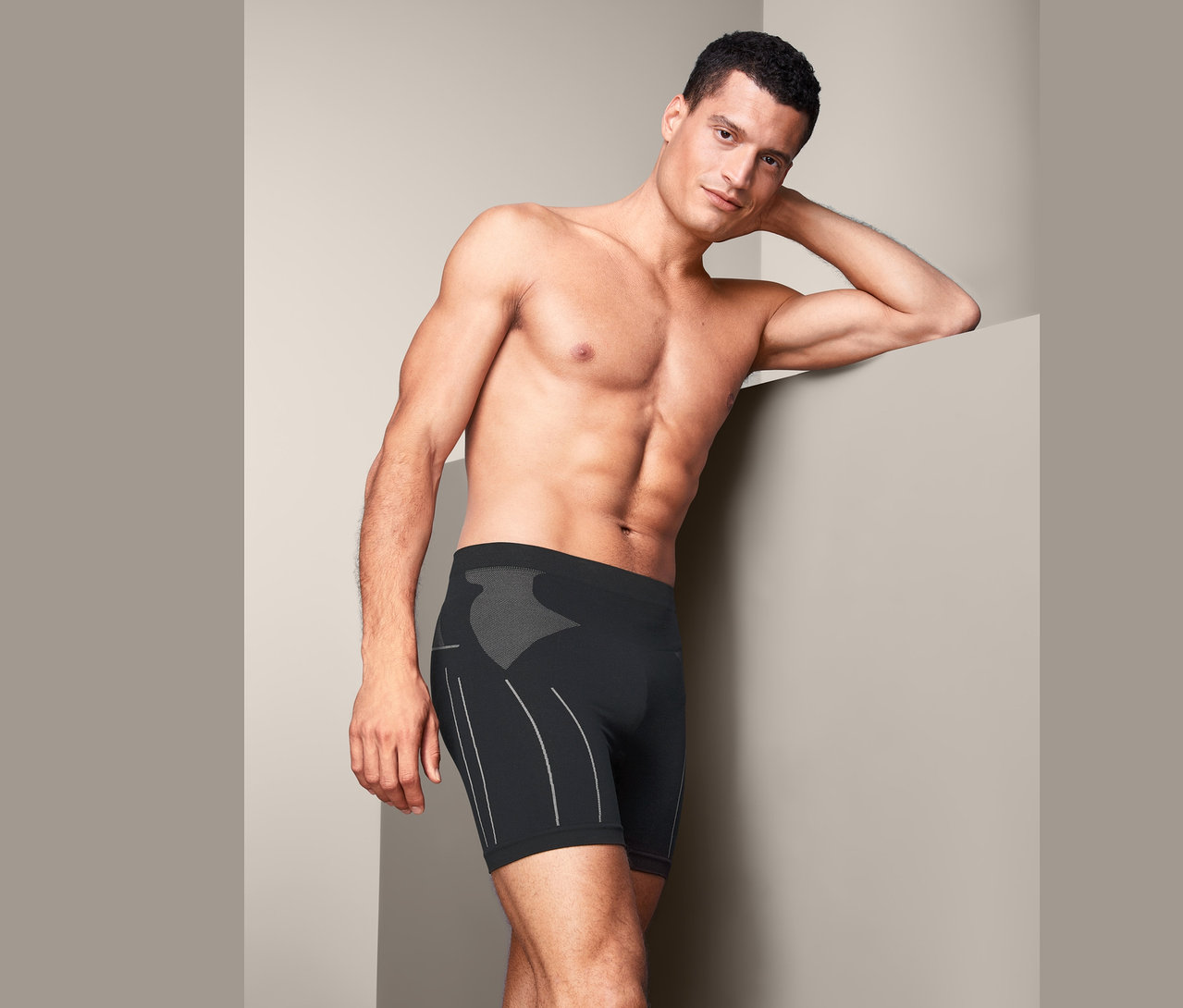 Mann lehnt an Wand, trägt Radunterhose.