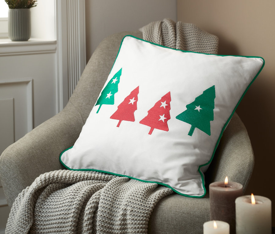 Dekokissenbezug mit Weihnachtsmotiv liegt auf einem Sessel.