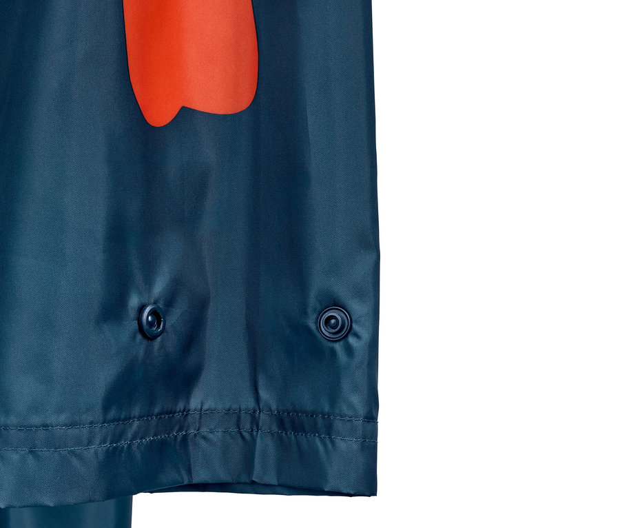 Detailansicht eines blauen Regenponchos mit orangem Muster und Druckknöpfen.