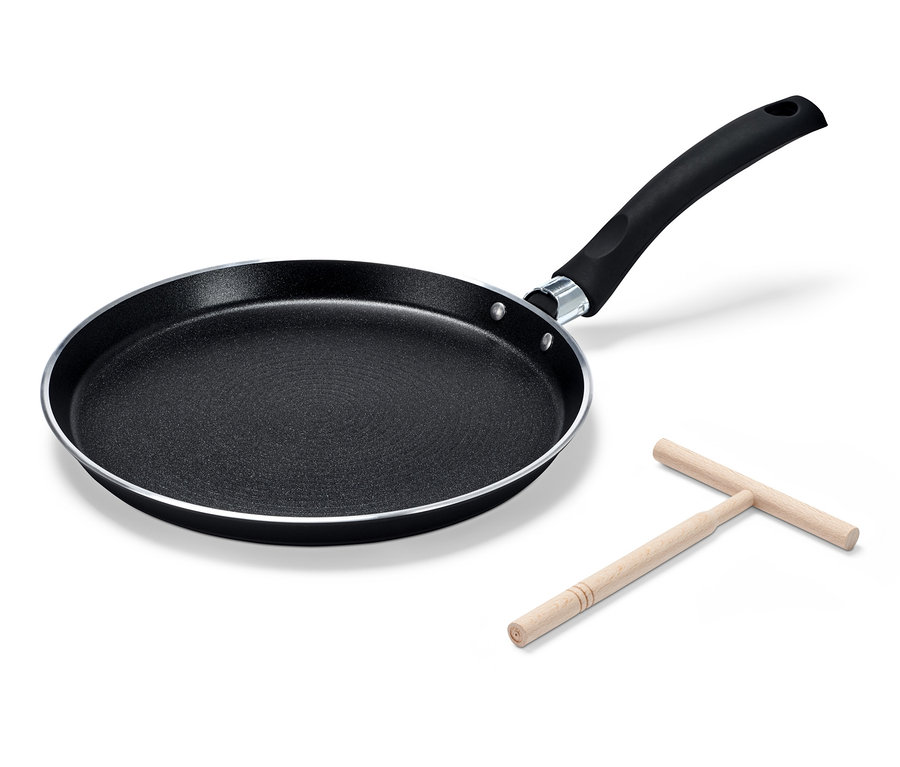 Eine schwarze BALLARINI Positano Crêpepfanne aus Aluminium und ein hölzerner Teigverteiler liegen auf einem weißen Hintergrund.