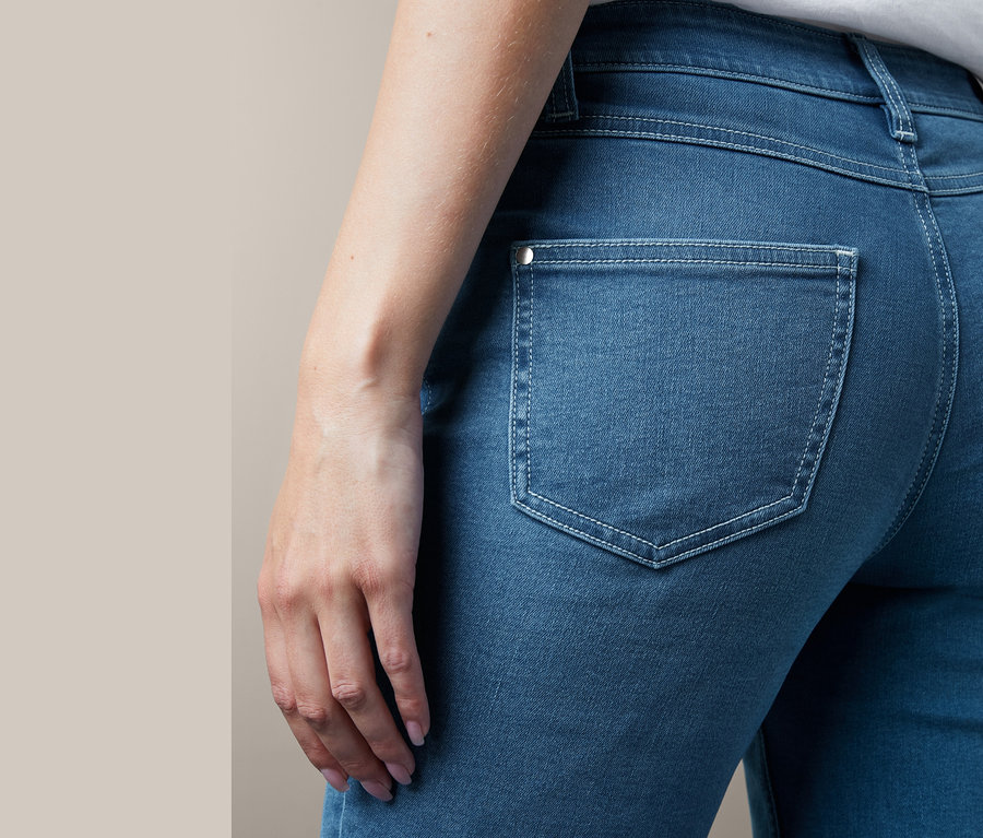 Detailaufnahme einer Frau, die eine Slimfit-Jeans trägt, mit einer Gesäßtasche mit Ziernähten.