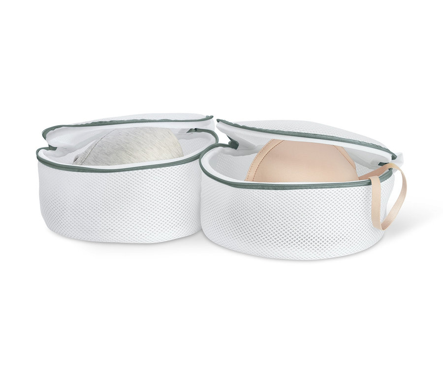 Zwei weiße BH-Wäschenetze, in denen sich jeweils ein BH befindet.