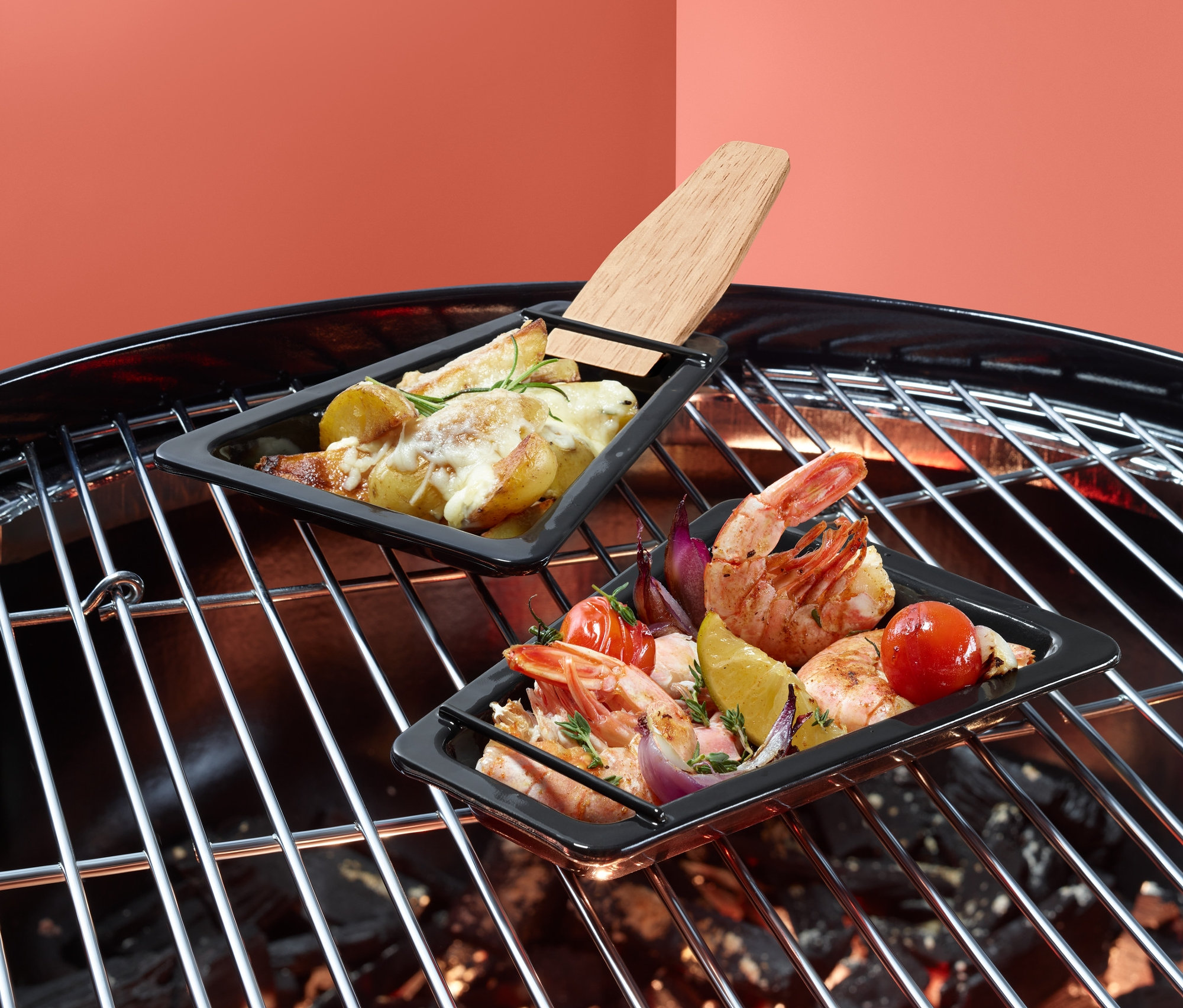 Zwei Grill-Pfännchen mit Essen auf einem Grill.