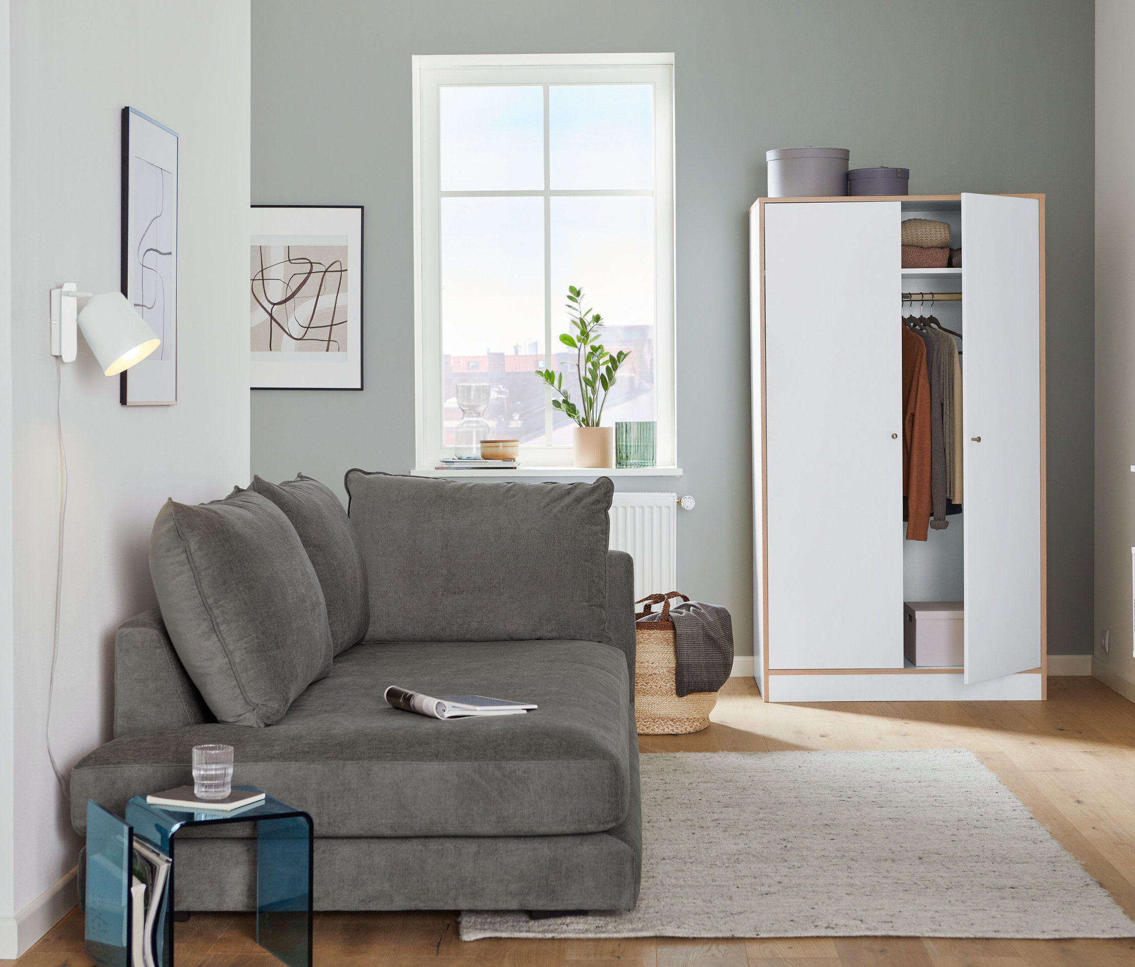 Im Wohnzimmer stehen eine graue SCAPA Recamiere »Tofta« mit Armlehne links und eine weiße Wandleuchte aus Metall.